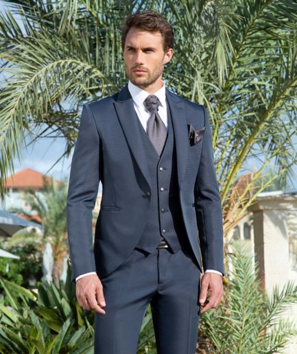 Un chico joven posando con un traje de ceremonia sencillo.