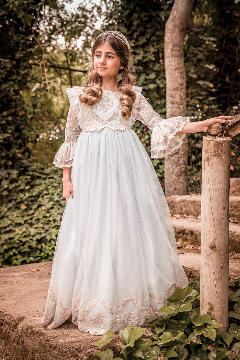 Una niña lleva un vestido de primera comunión con infinidad de detalles bordados.
