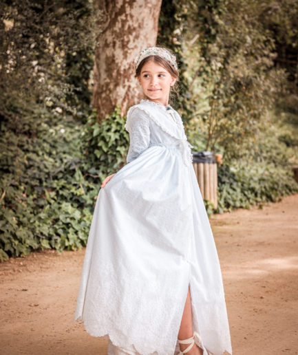 Niña feliz moviendo su vestido en primera comunión.