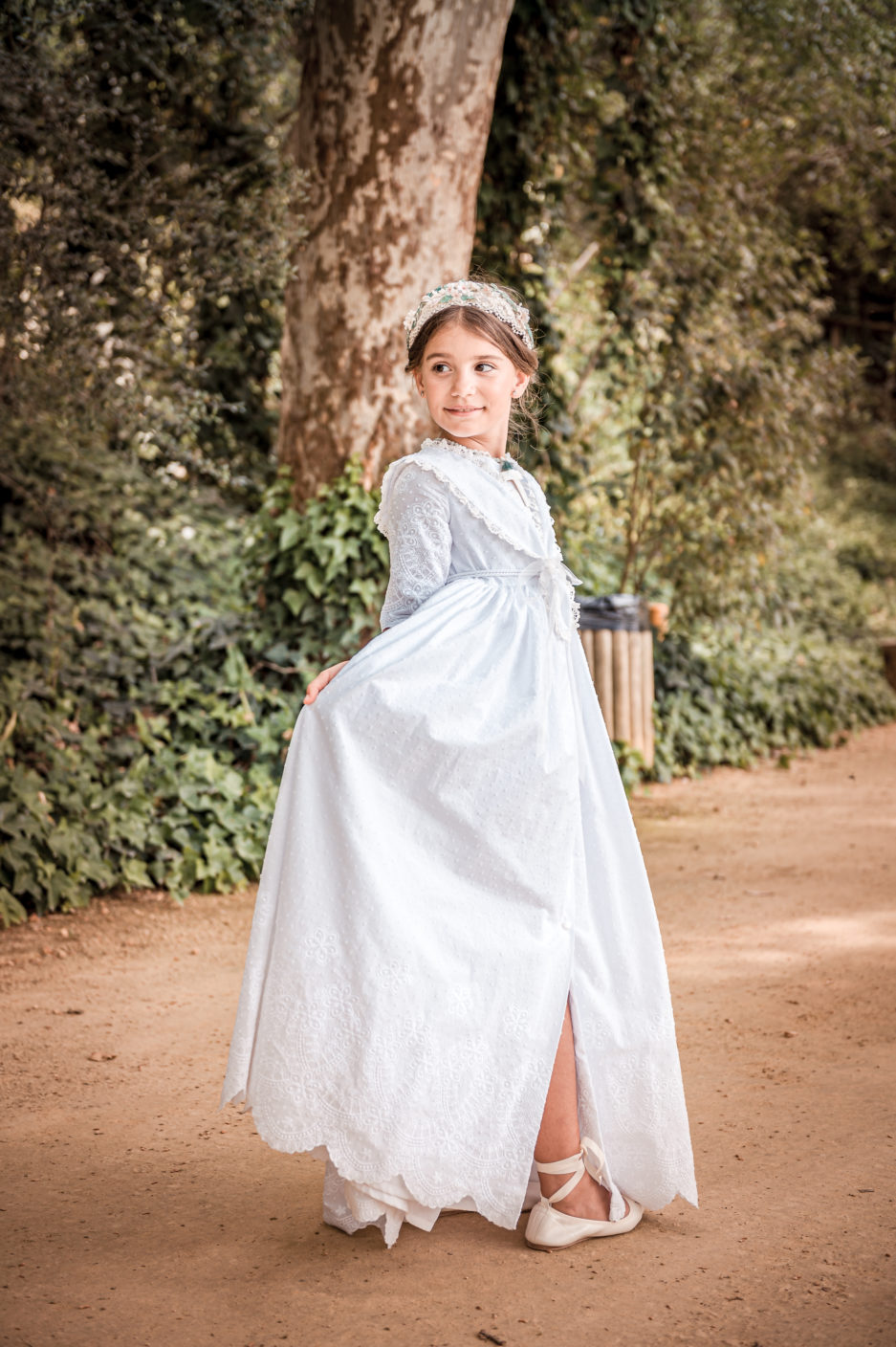 Niña feliz moviendo su vestido en primera comunión.