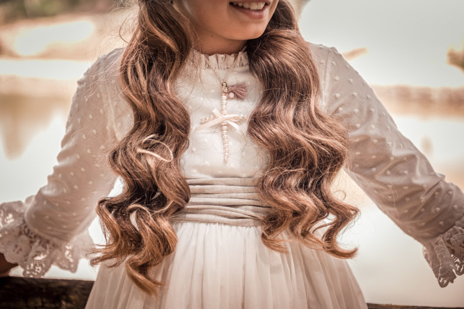 Niña luce un vestido de primera comunión con bordados, una cadena y un fajín.